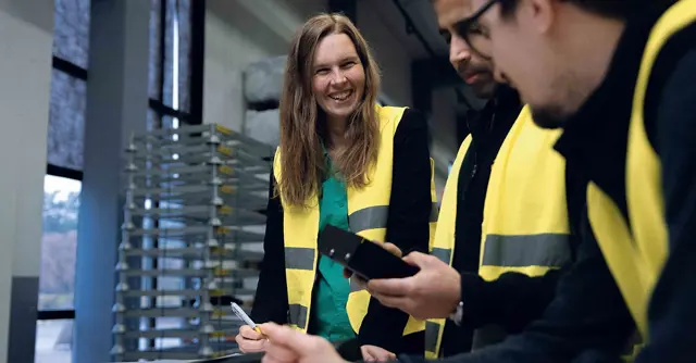 Tre personer pratar i en produktionsmiljö
